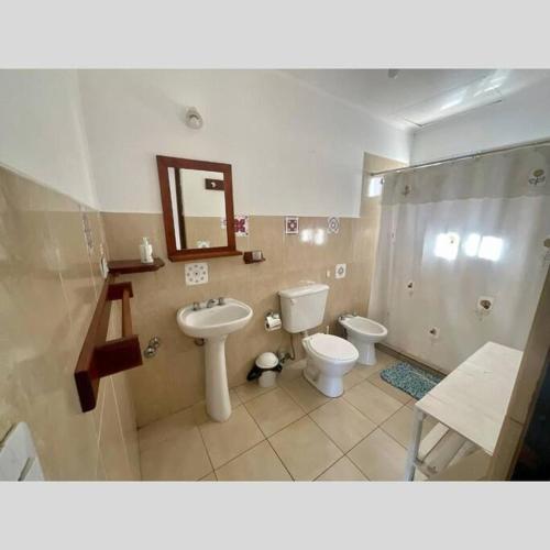 een badkamer met een wastafel, een toilet en een spiegel bij Casa Nehuen in Lago Puelo