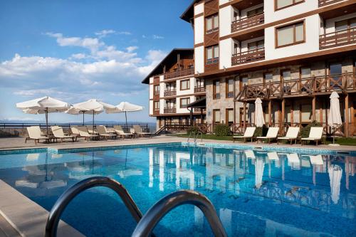 einem Pool vor einem Gebäude mit Stühlen und Sonnenschirmen in der Unterkunft Green Life Bansko in Bansko