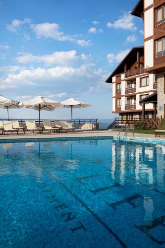 a swimming pool with chairs and umbrellas next to a building at Green Life Bansko in Bansko