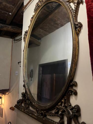 ein verzierter Spiegel an einer Wand mit einem Fernseher in der Unterkunft La Preta Nera in Giuliano di Roma
