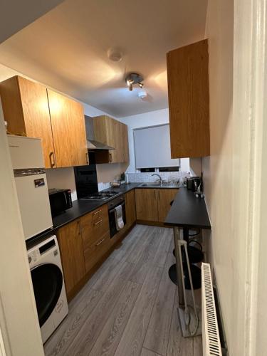 a small kitchen with wooden cabinets and a table at Herbies Stay in Southend-on-Sea