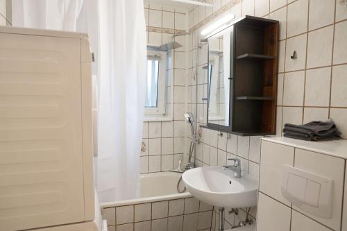 a white bathroom with a sink and a bath tub at Cozy Apartment in Eppelheim in Eppelheim