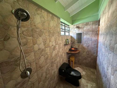 a shower in a bathroom with a stone wall at Mabrika Resort Dominica in Guillet