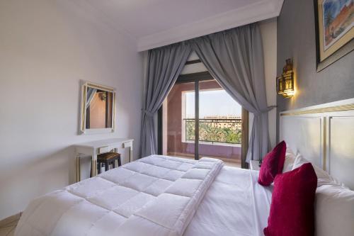 1 dormitorio con 1 cama blanca grande con almohadas rojas en Mogador Menzah Appart Hôtel, en Marrakech