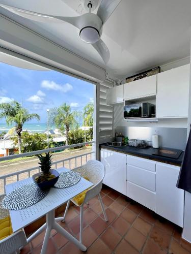 a kitchen with white cabinets and a table and a view of the ocean at Chez Valérie et Pascal in La Trinité