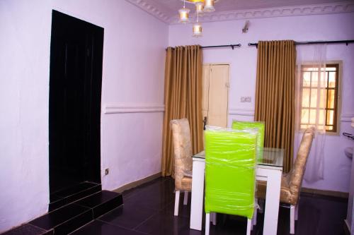 ein Esszimmer mit grünen Stühlen und einem Tisch in der Unterkunft Xproject Homes in Ibadan