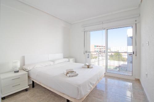 カネット・デ・ベレンゲルにあるGlobal Properties, Las dachas 1 - Apartamento en primera línea de playaの白いベッドルーム(ベッド1台、大きな窓付)