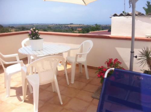 - Balcón con mesa blanca y sillas en Pezzino Green Home, en Agrigento