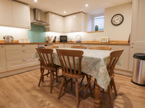a kitchen with a table with chairs and a clock on the wall at St Mary's Cottage in Windermere