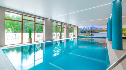 a large swimming pool with blue water in a house at Apartamenty Good Time- Stone Hill II in Szklarska Poręba