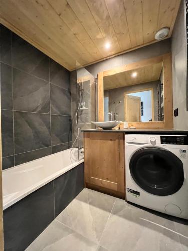 une salle de bain avec une machine à laver et un lavabo dans l'établissement Magnifique appartement de standing avec terrasse à Plagne Centre, à La Plagne Tarentaise