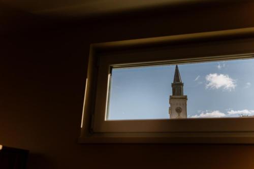 a view of a clock tower through a window at Apartman Zamak Sombor in Sombor