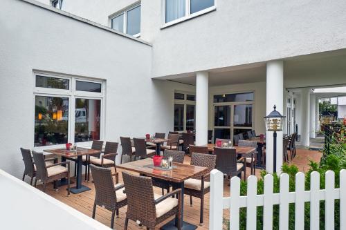 a patio with tables and chairs and a white fence at H+ Hotel Darmstadt in Darmstadt