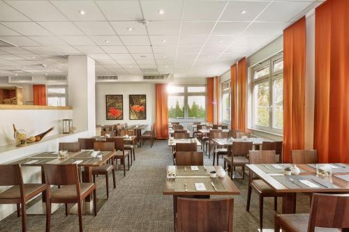 a restaurant with wooden tables and chairs and windows at H+ Hotel Darmstadt in Darmstadt