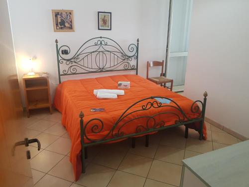 ガリポリにあるAppartamenti Boito Lido San Giovanniのベッドルーム1室(オレンジのシーツとタオルが入ったベッド1台付)
