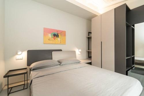 科莫的住宿－Appartamento moderno a 2 minuti dal duomo di Como，卧室配有白色的床和墙上的绘画作品