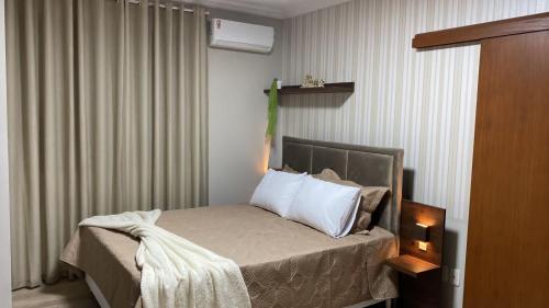 Dormitorio pequeño con cama con almohadas blancas en Residencial Don Alfredo-Luxo Gramado 2 km do centro locação de temporada en Gramado