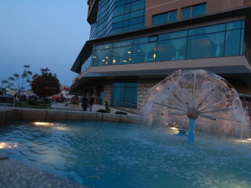 une fontaine dans une piscine en face d'un bâtiment dans l'établissement Hotel Esplanada, à Tulcea