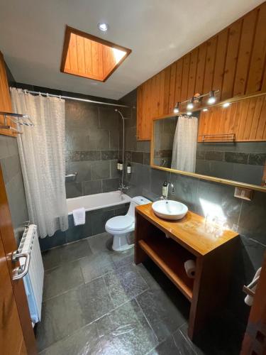 a bathroom with a sink and a toilet and a tub at Hotel Costanera Pucón in Pucón