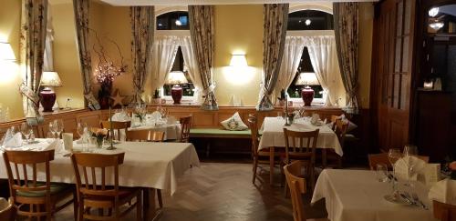 un restaurante con mesas y sillas blancas y ventanas en Gasthaus Sternen Post en Oberried