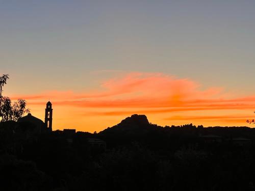 a clock tower with a sunset in the background at Hôtel confidentiel Le Grecale in Pianottoli-Caldarello