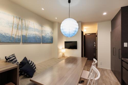 a dining room with a table and a light fixture at vacation rental SARAKU 茶楽来 in Osaka