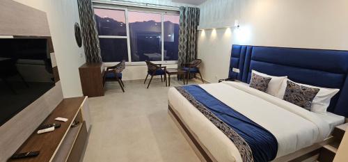 a bedroom with a bed with a blue headboard and a television at Tranquil Inn Mashobra in Shimla