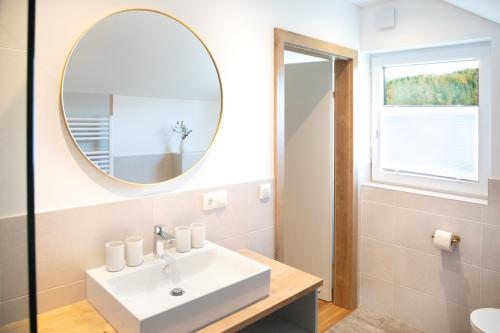 La salle de bains est pourvue d'un lavabo et d'un miroir. dans l'établissement Moosaik Appartements, à Strobl