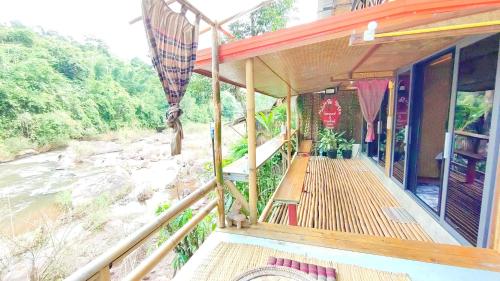 a porch of a house next to a river at โฮมสเตย์ เนเจอร์ เดอ สะปัน in Ban Huai Ti