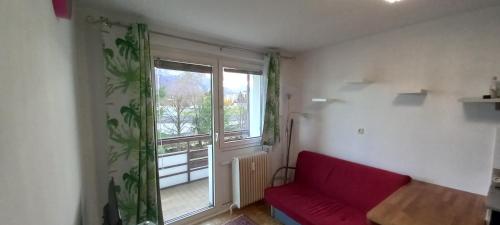 a living room with a red couch and a large window at Wohnung in Bahnhofsnähe mit Balkon - 35 m2 in Gmunden