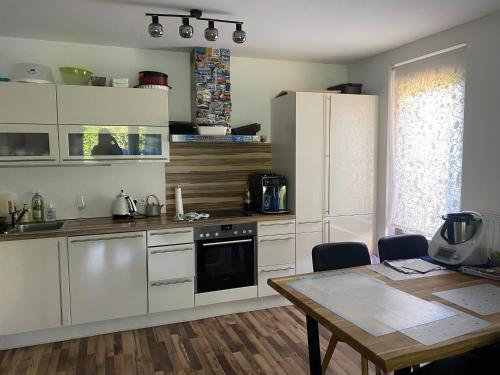 una cocina con armarios blancos, una mesa, una mesa y un tocador en Tolle 3 Zimmer Wohnung mit Garten, en Viena