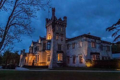 an old castle is lit up at night at Lough Eske Castle in Donegal