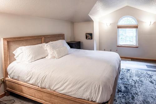 a bedroom with a bed with white sheets and a window at Cozy Cannon Beach Condo in Cannon Beach