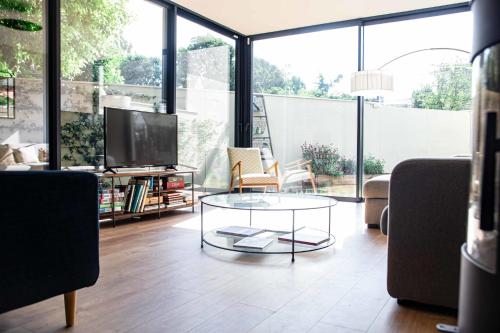 a living room with a glass coffee table and a tv at Cosy house near the Parc Bordelais in Bordeaux