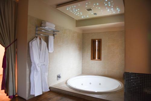 a bathroom with a large tub and a robe at Glenskirlie Castle Hotel in Banknock