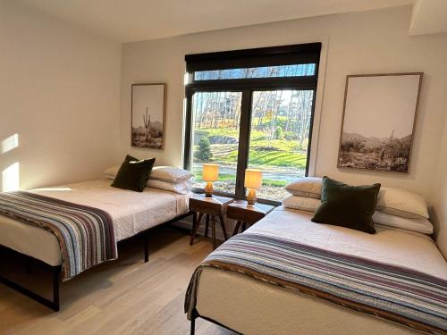 2 Betten in einem Zimmer mit Fenster in der Unterkunft Verbier New Luxurious Condo 2bdrm spa-pool-sauna in Mont-Tremblant