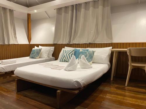 two beds in a room with a chair at Casitas de Boracay in Boracay