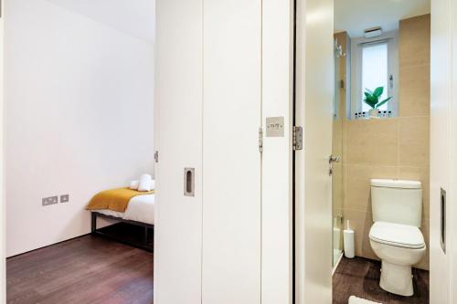 a bathroom with a toilet and a bed at Welcome London Covent Garden in London