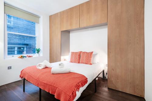 a bedroom with a bed with two towels on a red blanket at Welcome London Covent Garden in London