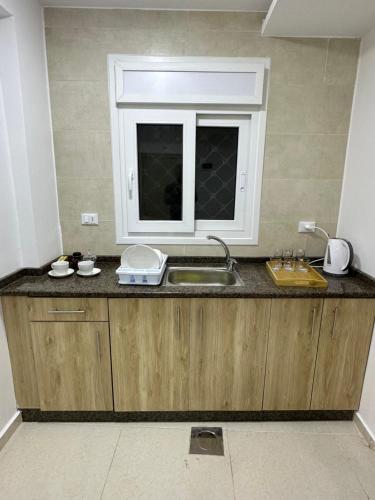 um balcão de cozinha com um lavatório e uma janela em Karak Plaza Apartments em Kerak