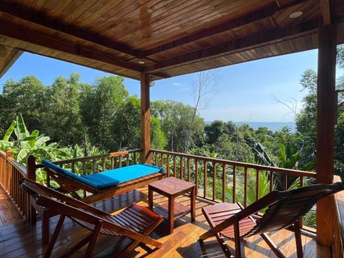 a deck with chairs and a table and a bench at COZY HOME PHU QUOC in Phu Quoc