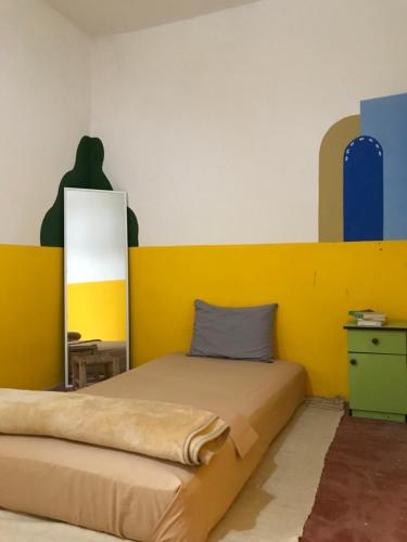 a bedroom with a bed with a yellow headboard at Green IGR Guesthouse in Agadir