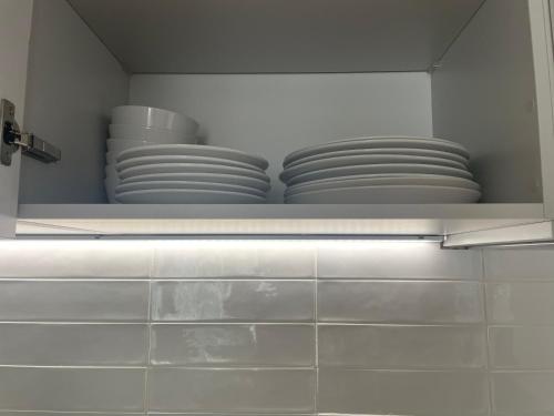 a white shelf with plates and bowls in a kitchen at The Axium Superior Apartment in Birmingham