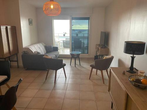 ein Wohnzimmer mit einem Sofa, Stühlen und einem Tisch in der Unterkunft Le Ti Mimosa - Lagon in Saint-Leu
