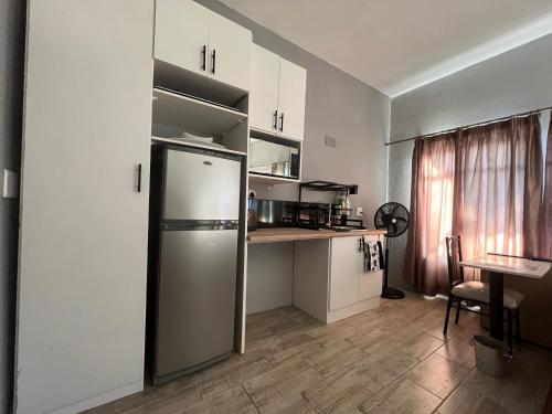 a small kitchen with a refrigerator and a table at Kiewiets Creek Guesthouse in Pretoria