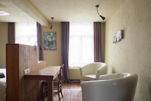 een kamer met een bureau, stoelen en een bed bij Poëziehotel Surplace in Bever