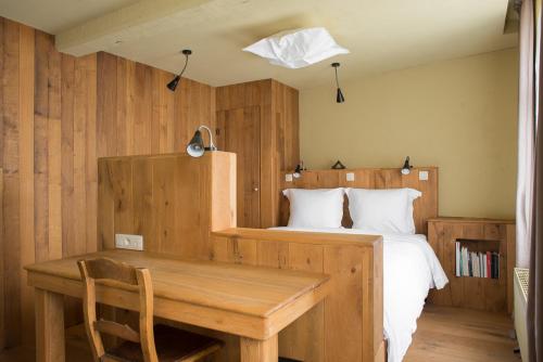 Poëziehotel Surplace في Bever: غرفة نوم مع سرير مع طاولة خشبية ومكتب