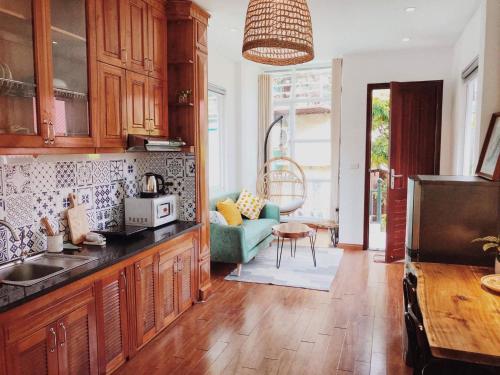 a kitchen with wooden cabinets and a living room at Azalea Apartment in Hanoi