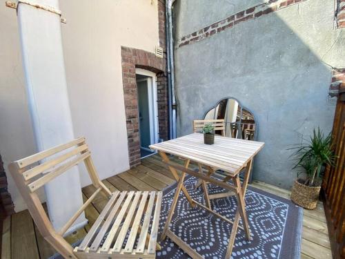 een houten tafel en 2 stoelen op een patio bij Studio avec terrasse à Deauville in Deauville
