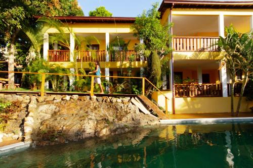 a woman standing in front of a house with a swimming pool at Villa Botanic Garden in Itacaré